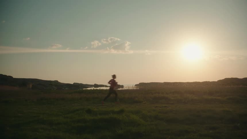 A woman is jogging outdoors in a grassland area