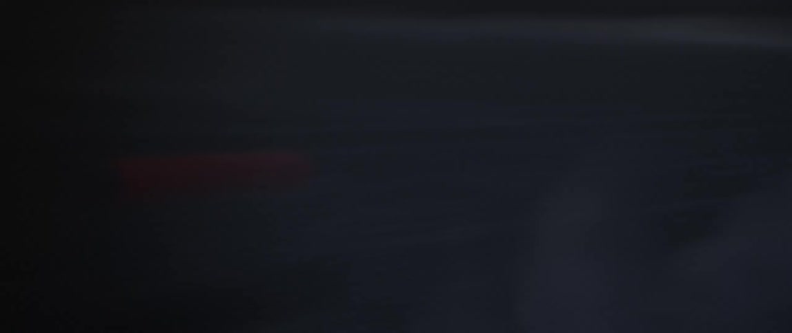 Silhouette of a motorcycle with he headlight on driving on a desert at evening