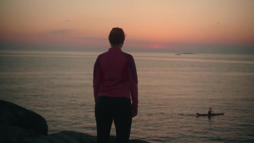 A woman staring out while a person canoes