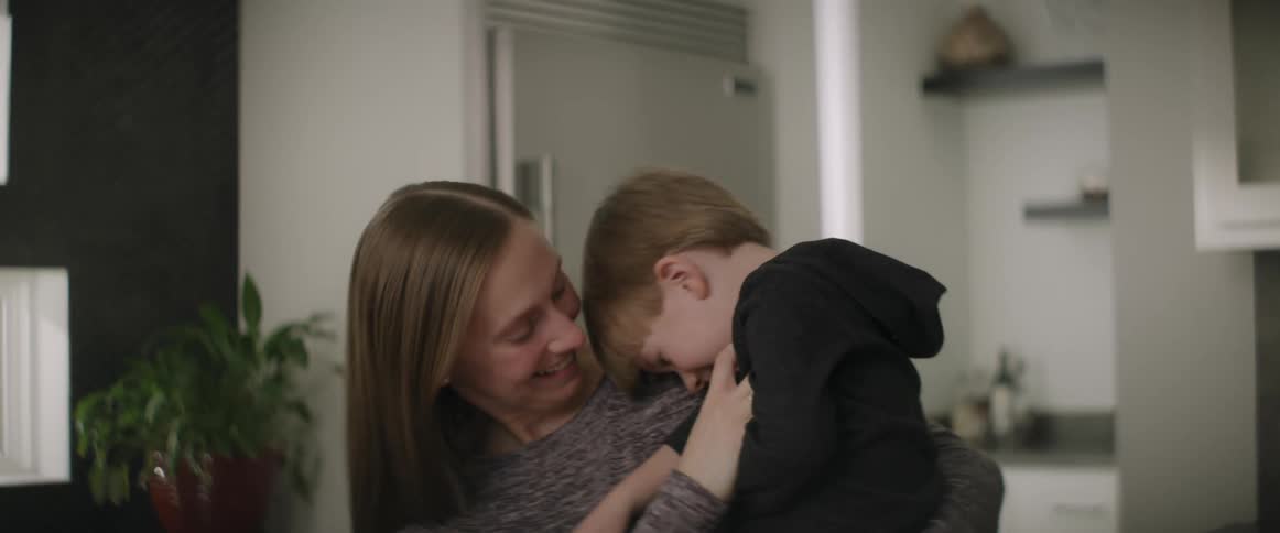Happy mother playfully tickles her son to make him laugh in the living room