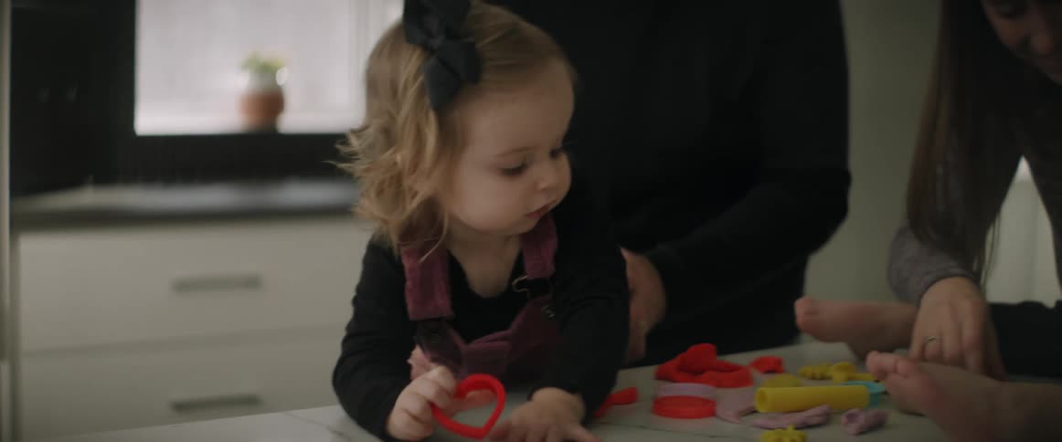 Mom and dad are with their two young children as they play on the table making shapes with play dough