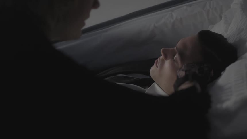 A woman leans over a casket of the deceased