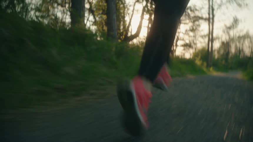 Female jogger runs along path on sunny day