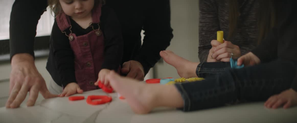 Mom and dad with son and daughter playing with play doh and cutouts on the kitchen counter