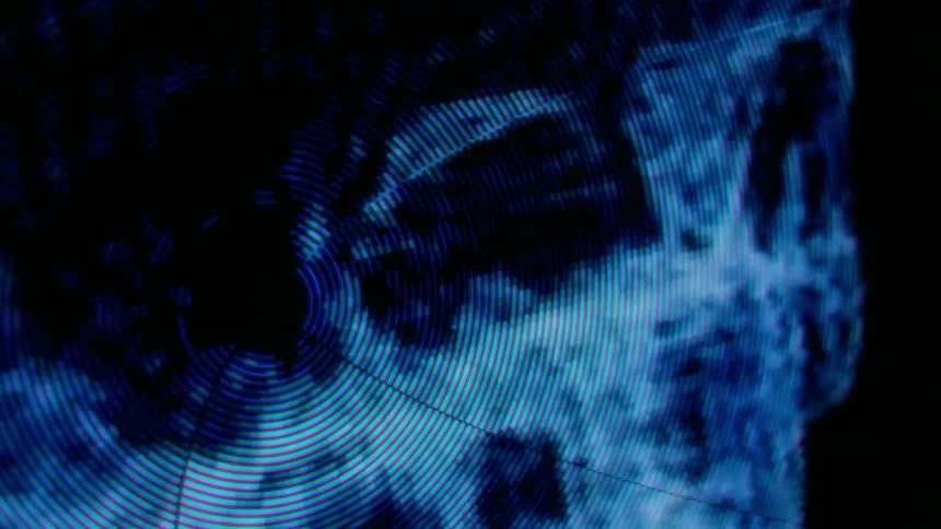 Concentric lines and circles fill surface of rotating blue skull image against a black background