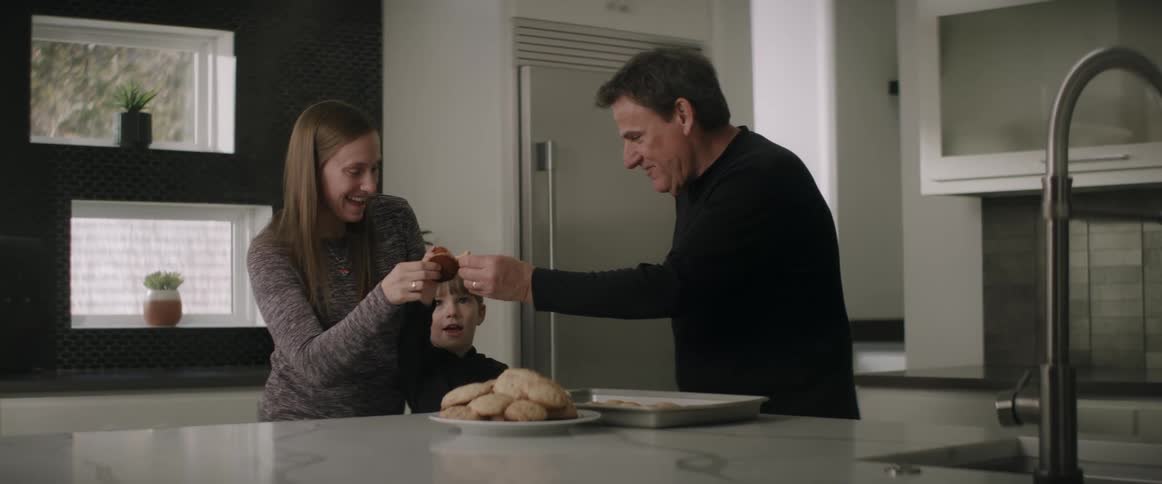 Family of three enjoying cookies in the kitchen at home