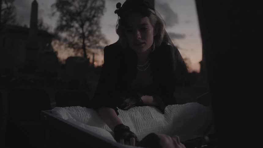 A woman leans over the casket of a deceased man