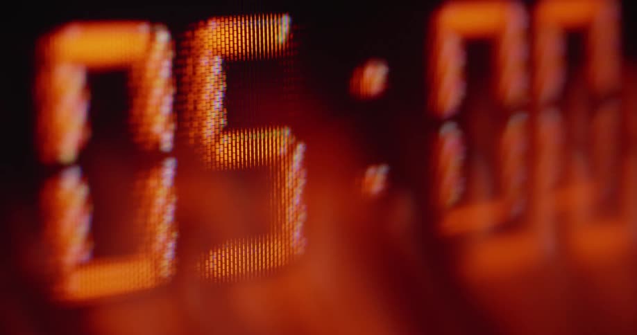 Stressful close up of pixelated display of an old digital clock running a countdown causing suspense and tension