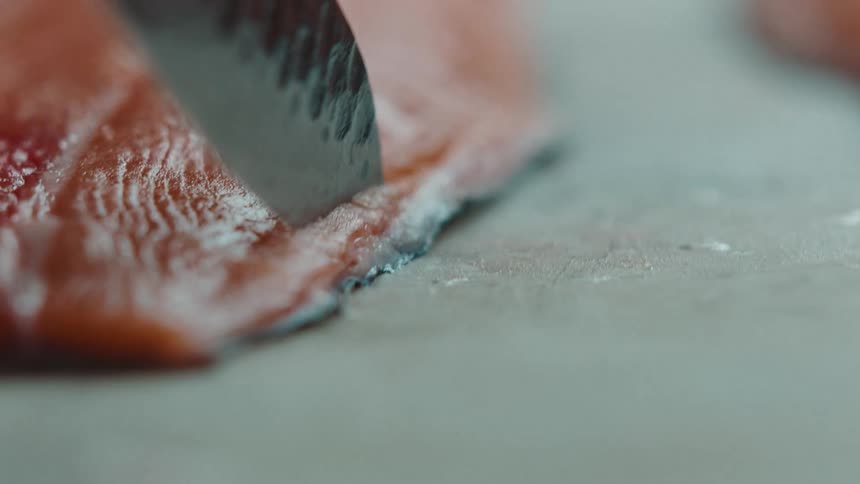 Cook cuts salmon steak with knife