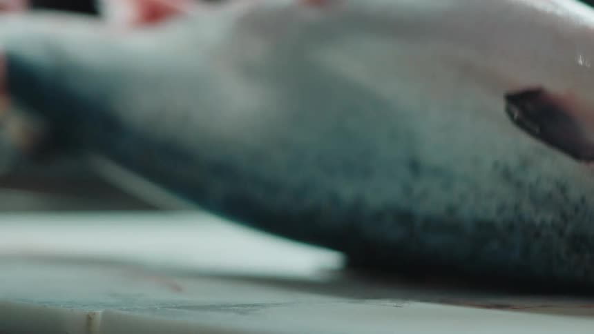 Chef flips fish on chopping board to wipe it down with a cloth