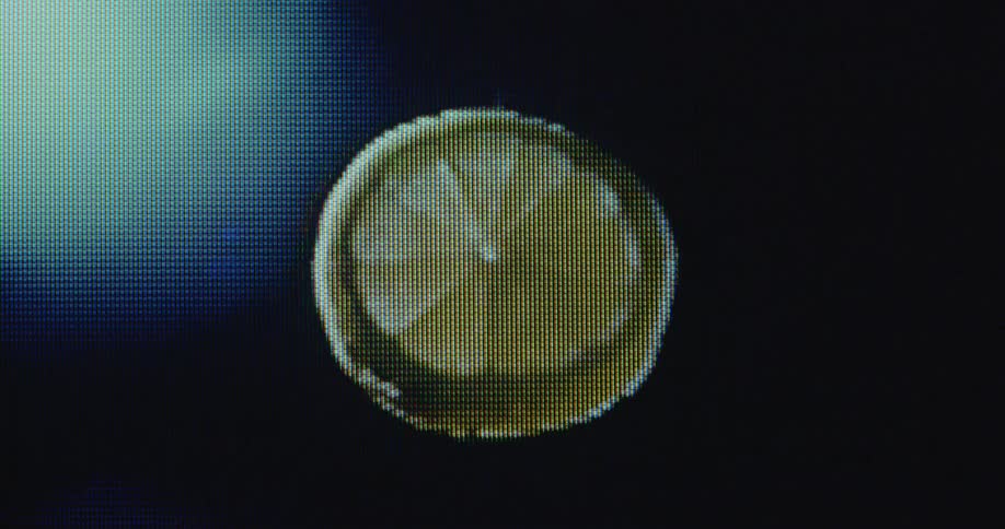 Close up of a pixelated floating spinning slice of lime or lemon dripping juice on old television screen