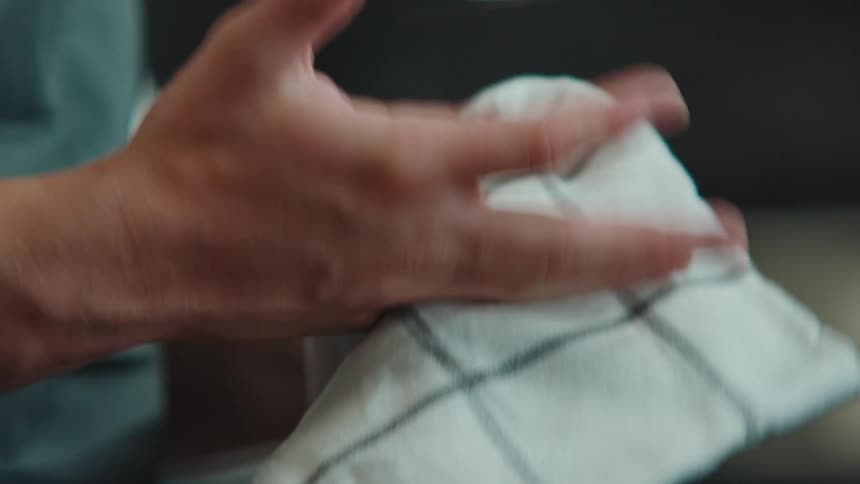 A man wipes his fingers with a kitchen towel