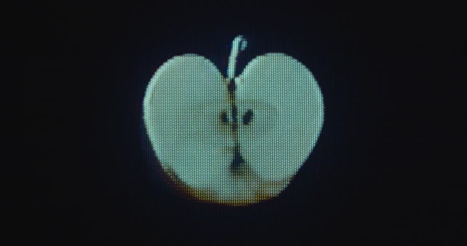 Close up of digitized turning 3D apple fruit cut in half on glitching vintage tube TV with RGB pixels