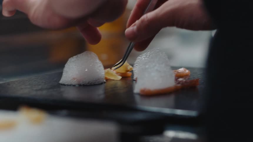 A cook is carefully plating a meal