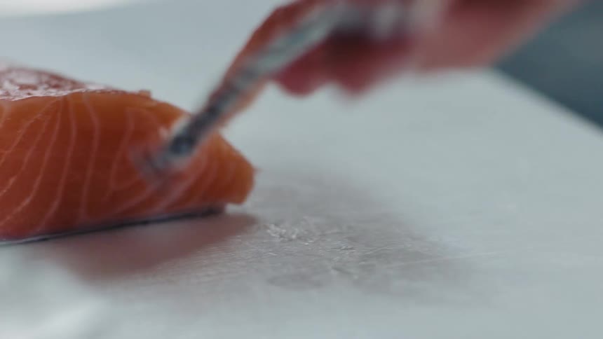 Cook slices salmon steak with knife in the kitchen