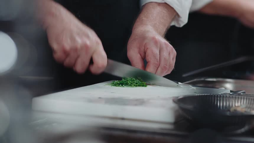 A chef is cutting food in the kitchen
