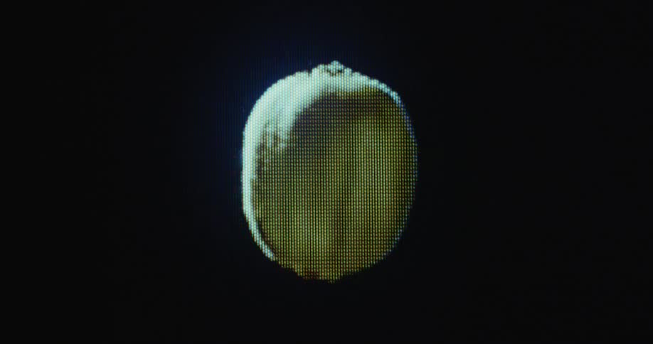 Macro shot of a pixelated rotating kiwi fruit floating in and out of focus on flickering retro computer screen with transformation