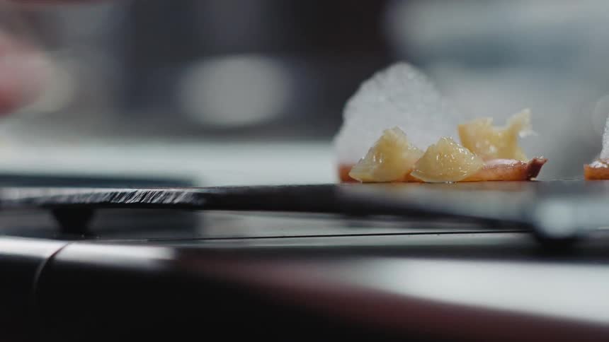 Close up of the hands of a chef serving a dish in the restaurant kitchen