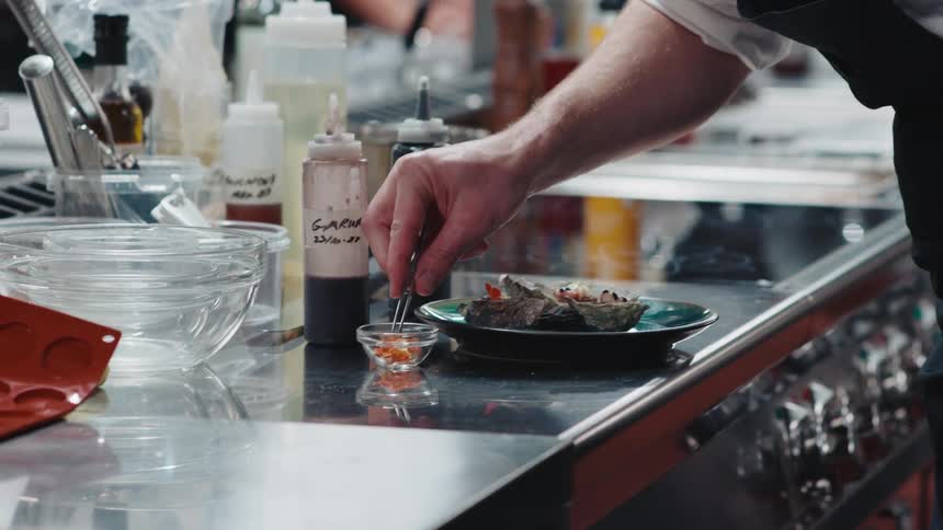 A chef plating a meal in a restaurant kitchen