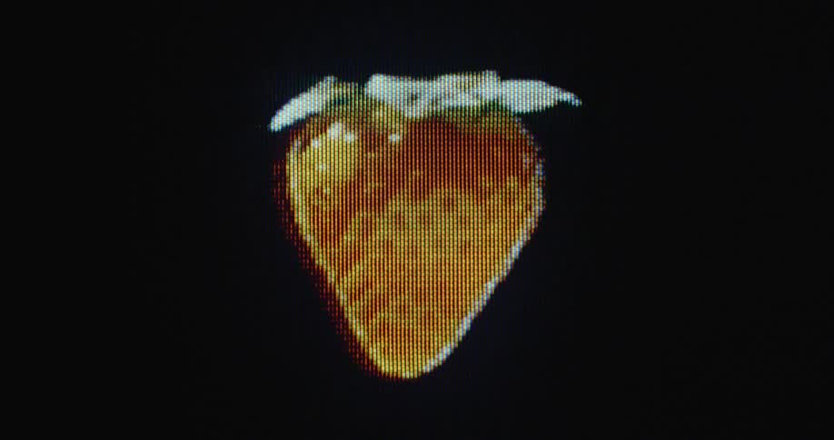 Futuristic shot of a pixelated fresh organic strawberry spinning with black background on glitching old television screen