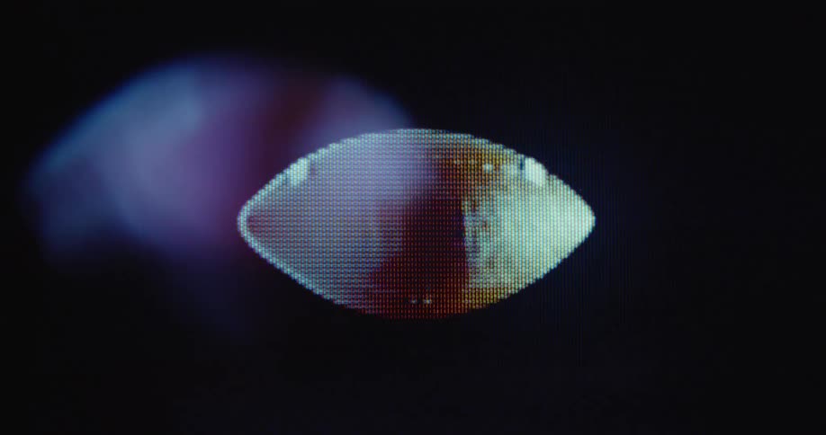 Close up of a pixelated American football spinning and flying on a flickering retro RGB TV screen