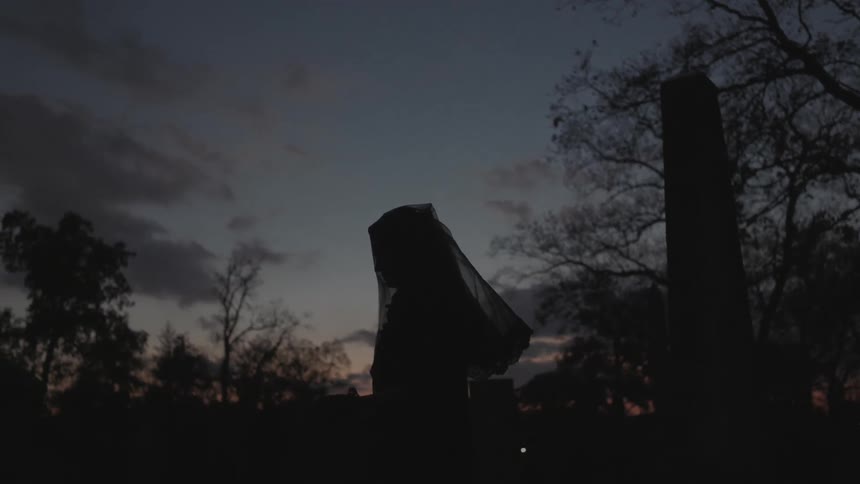 A woman puts a veil over her head at dawn