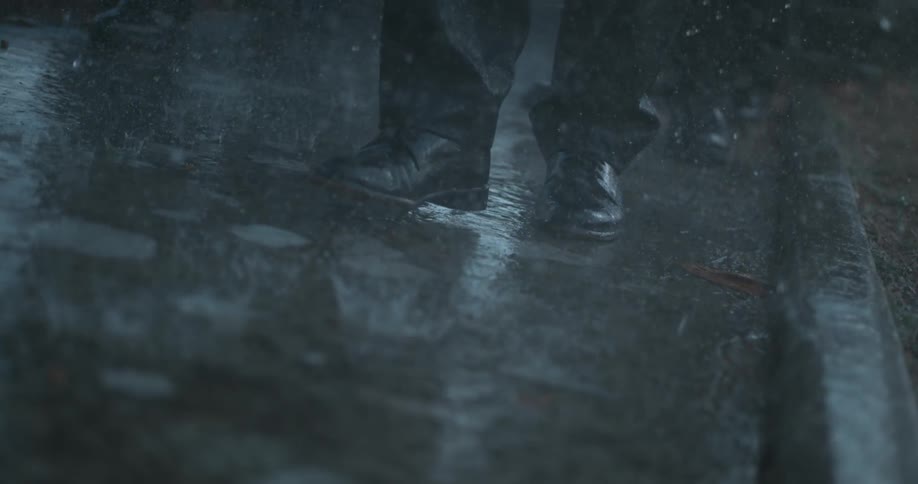 A man in dress shoes walks in the pouring rain
