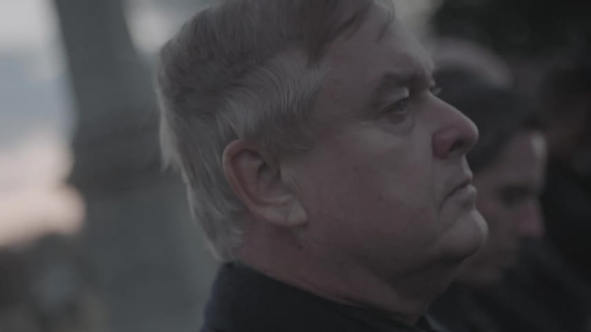Man removes his hat in a cemetery