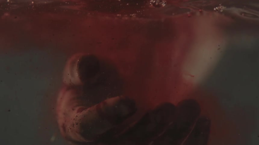 Hand falling into water with the red coming from it