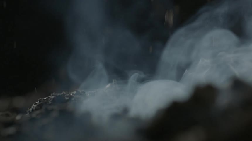 Smoke rises from a pile of ashes