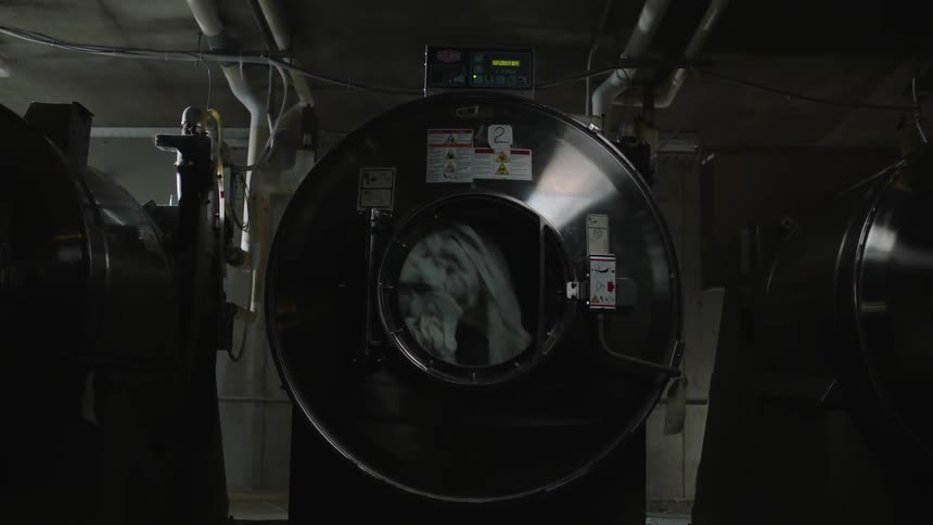 A commercial sized washing machine washes garments