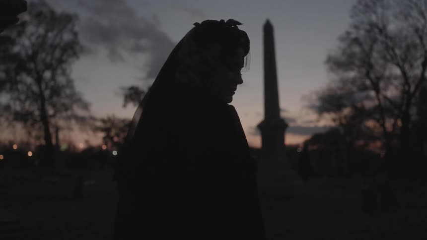 A woman in a veil is outside after sunset