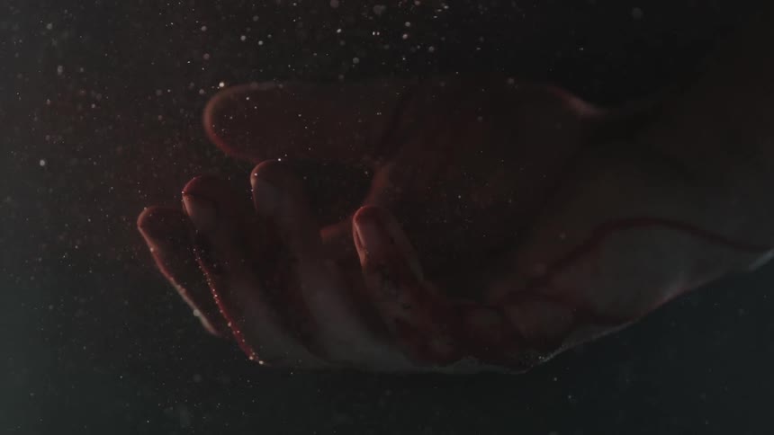 A bloody hand falls into the water