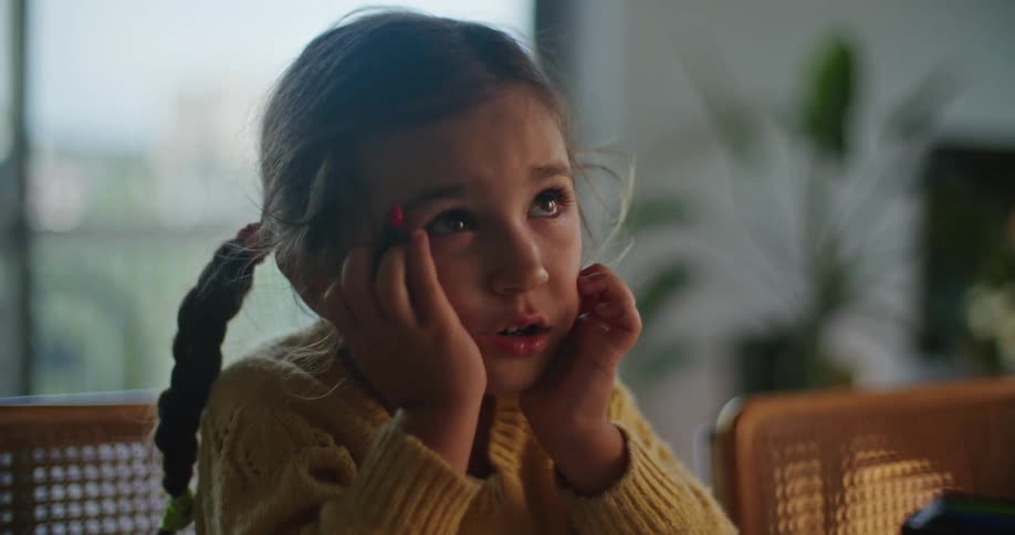 Close up of a bored girl looking at her father while sitting in the kitchen at home