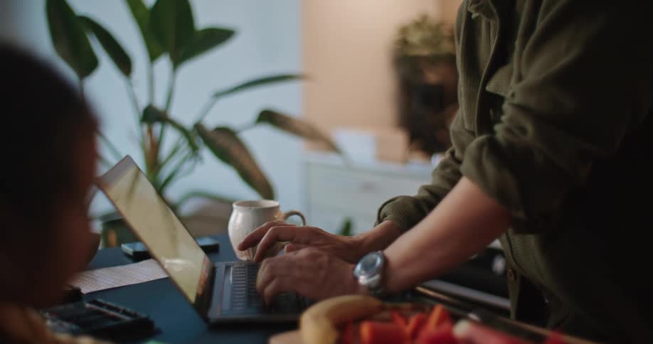 A man is typing on his laptop as he eats