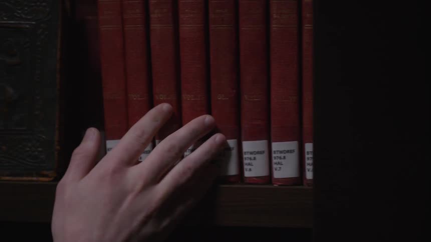 A person is looking through books in a library