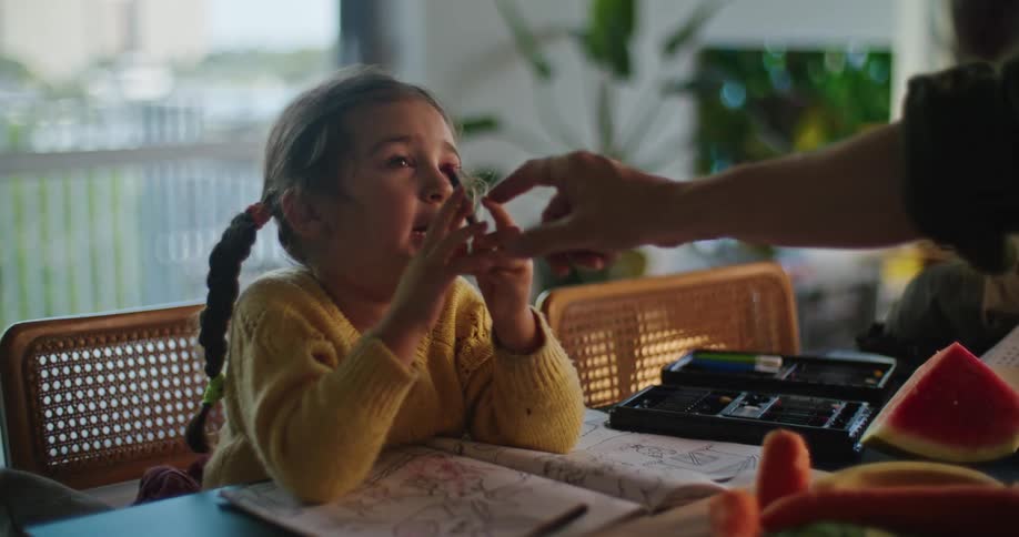 Mother and daughter are drawing together at the dining table after eating watermelon
