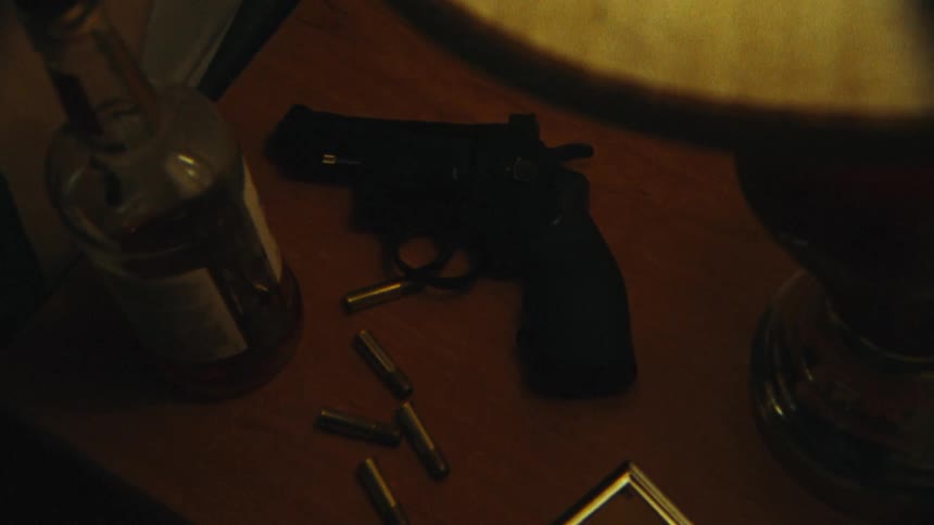 Bullets and gun lie on table with liquor bottle and lamp as flash shines briefly
