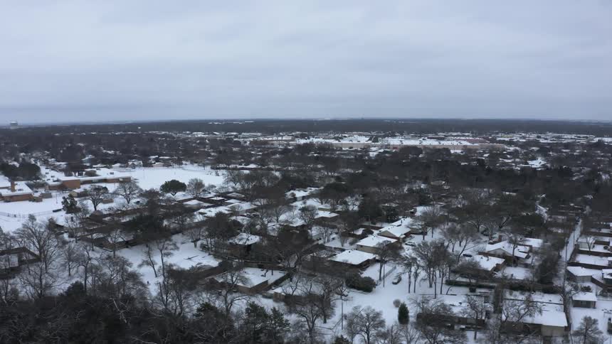 Groves border snow covered neighborhood streets under an overcast sky