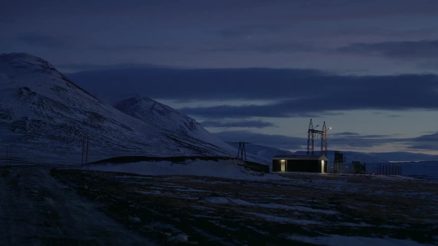 Buildings in the snowy countryside near a mountain at nightfall