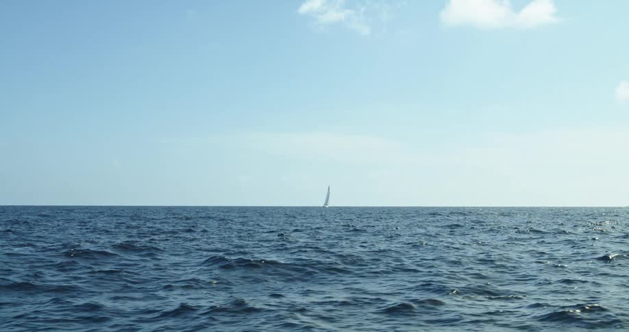 Sailboat on the distant ocean horizon at daytime