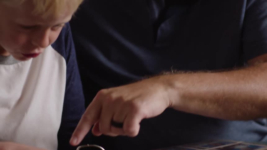 A man shows his son an album full of baseball cards