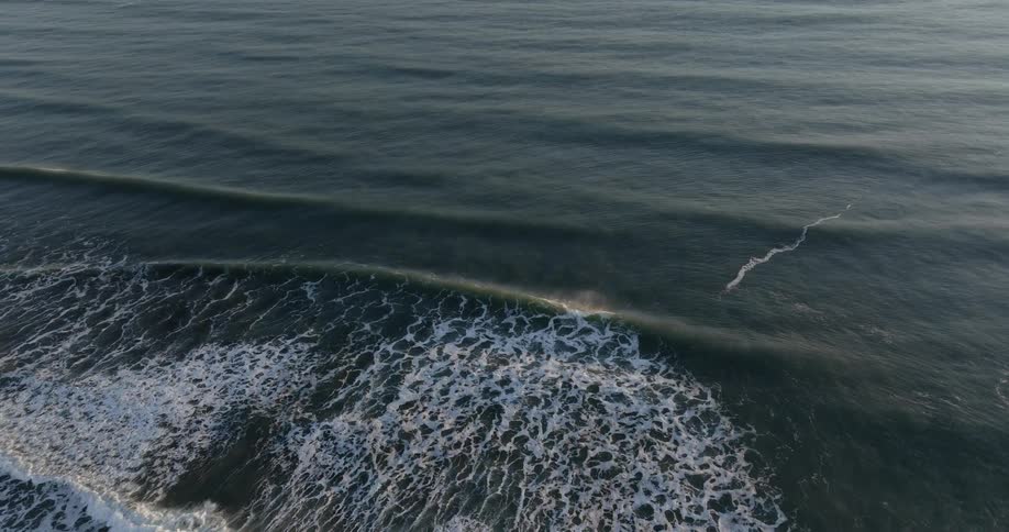 Aerial view of wavy sea at sunset