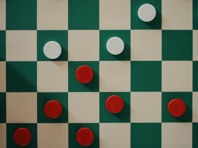 People playing a game of checkers on a white and green board