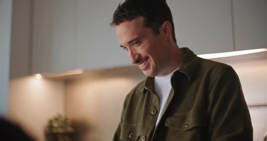 A man smiling and talking and leaning into a little girl as she eats