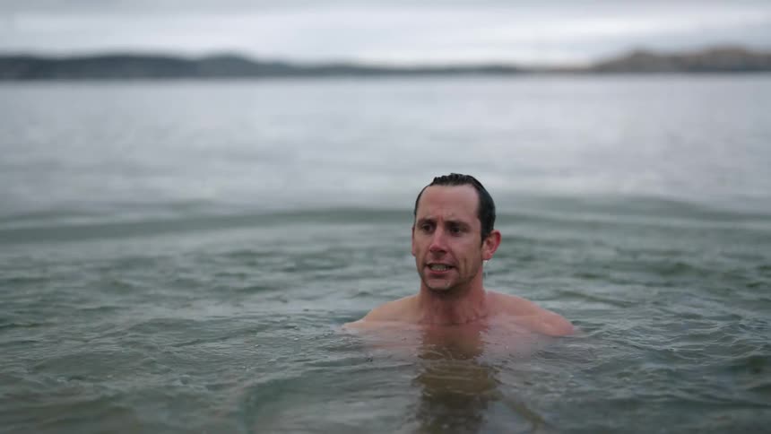 A man is swimming in ocean water at midday
