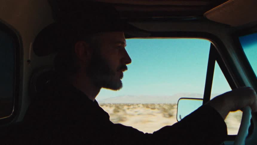 A man is driving a car through a desert area