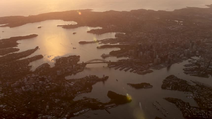An aerial of a dense city with water flowing through it and a bridge