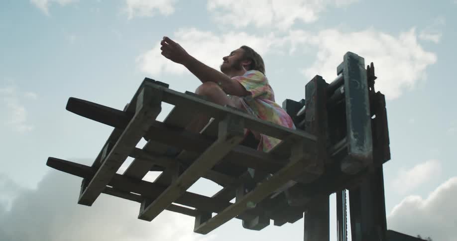 A man is meditating on a raised fork lift