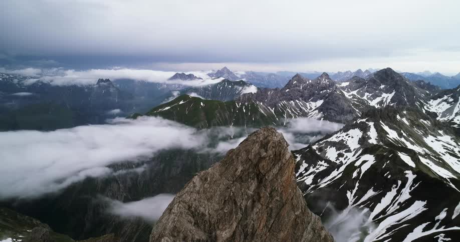 A mountain range covered in patches of snow on a cloudy day